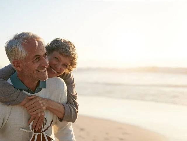 Smiling senior couple embraces while walking along a scenic beach