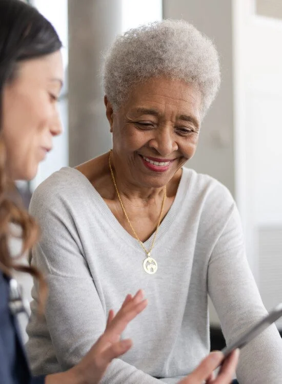 Older woman with team member looking at her phone