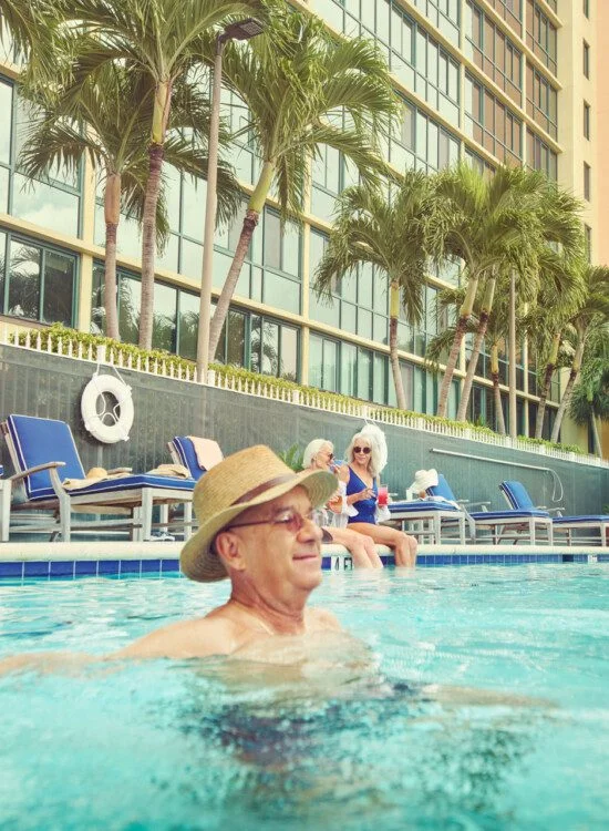A senior man in the pool with a hat