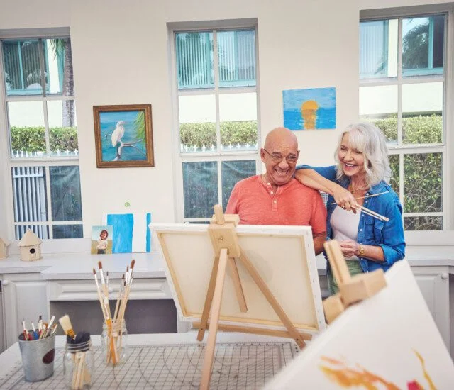 Two seniors laughing and looking at a painting