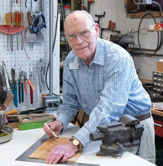 A senior man looking up from wood working