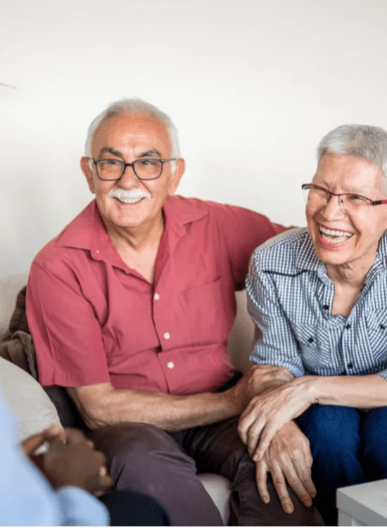 A senior couple talking to someone while on a couch
