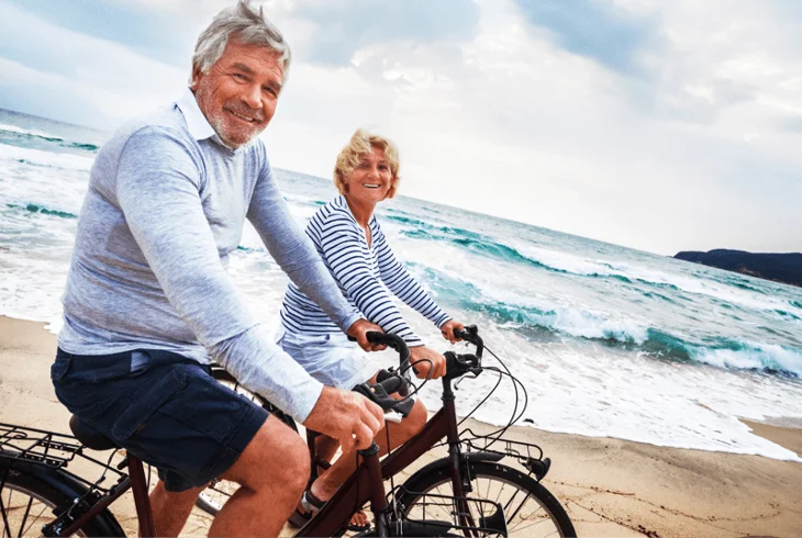 A senior couple on a bike ride on the beach