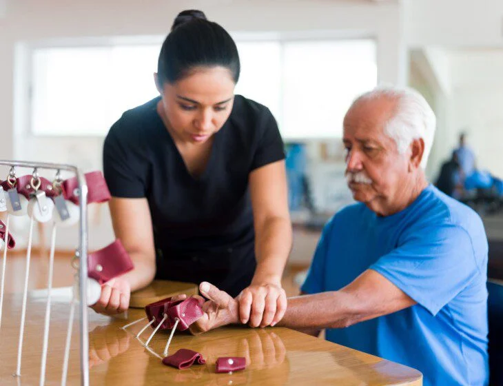A physical therapist helping a senior man do hand exercises