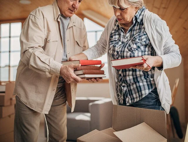 Two people, senior married couple unpacking boxes in their new apartment..