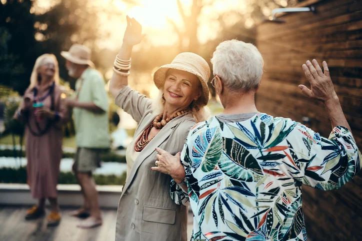 Carefree senior couple dancing on a party in the backyard at sunset.