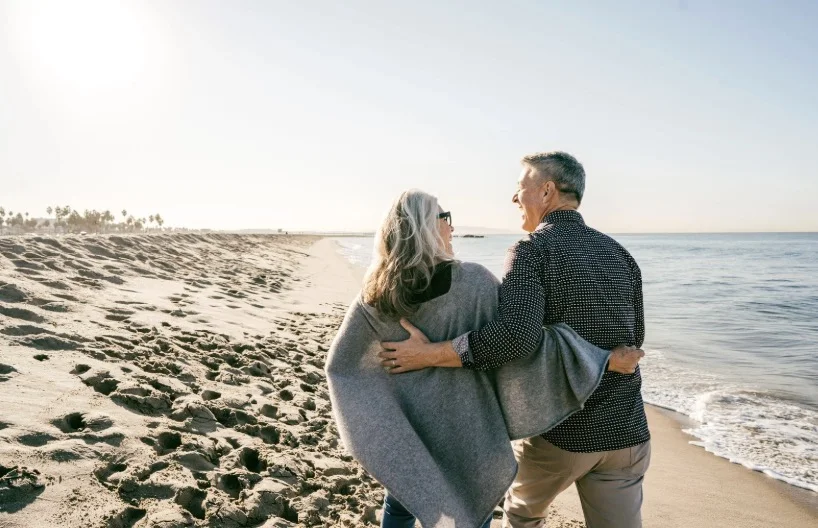 Senior couple walking along the beach near a Florida retirement community