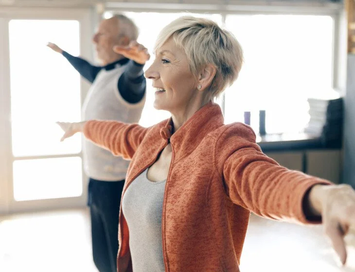 Active seniors in fitness class stretching arms