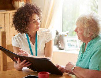 a care worker or medical professional or housing officer makes a house call to a senior client at her home . She is discussing the senior woman’s options on her digital tablet. a care worker or medical professional or housing officer makes a house call to a senior client at her home . She is discussing the senior woman’s options on her digital tablet.