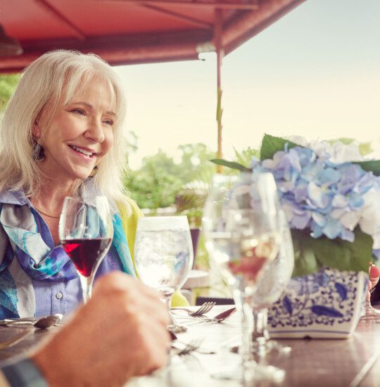 A senior woman laughing which having lunch with friends