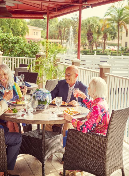 A group of seniors laughing and having lunch on a patio