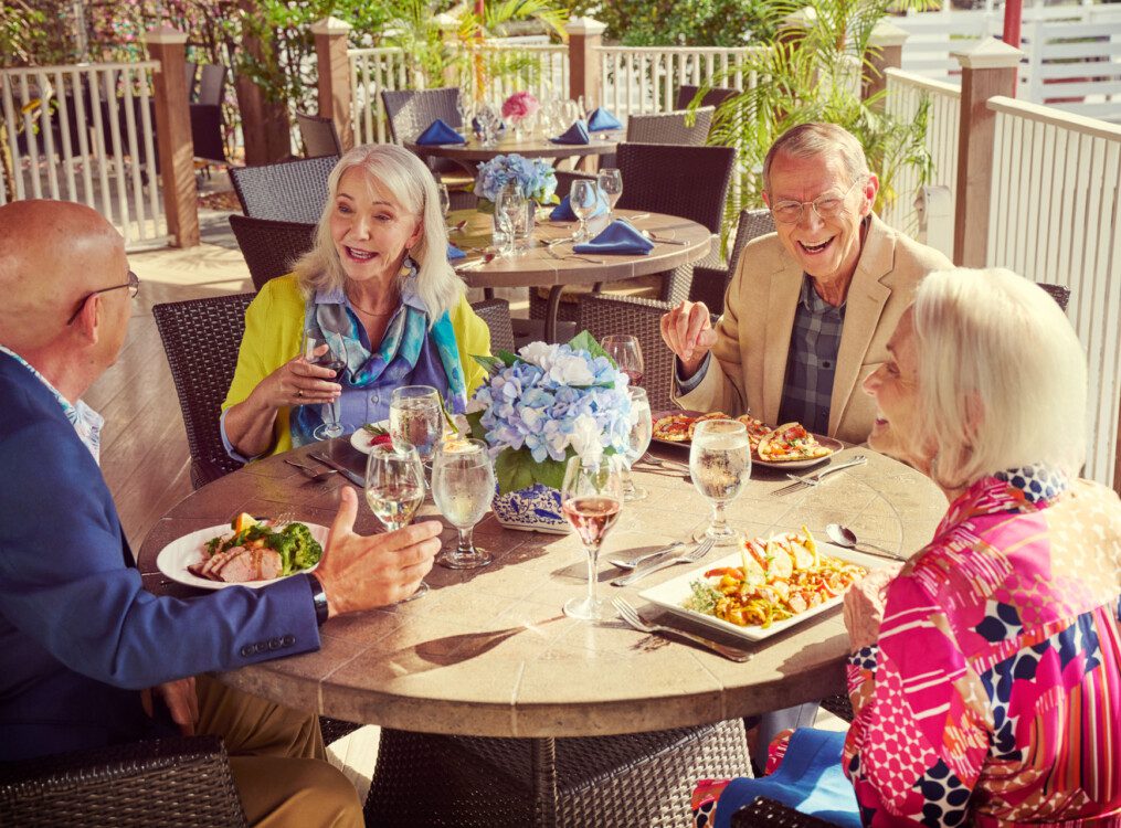 A group of seniors laughing and having lunch on a patio