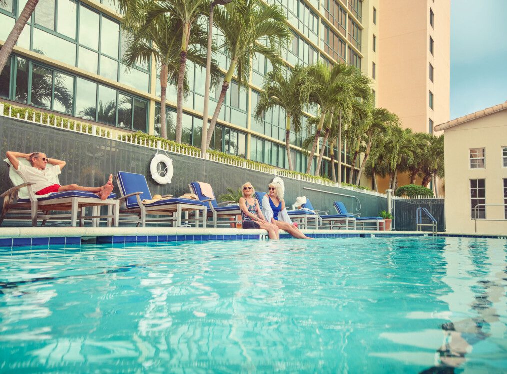 Two senior women laughing with their feet in the pool