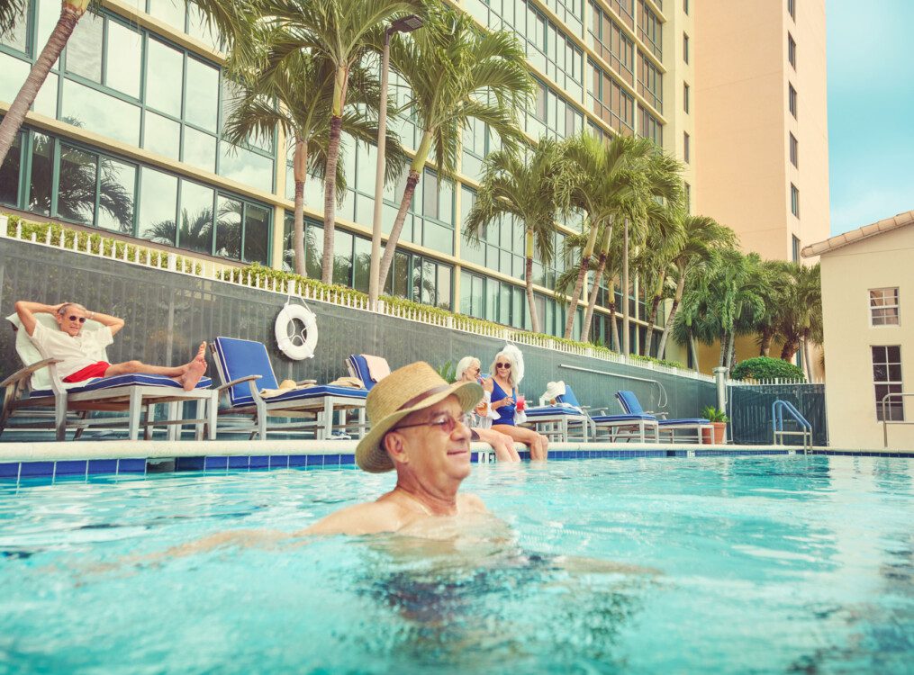 A senior man in the pool with a hat