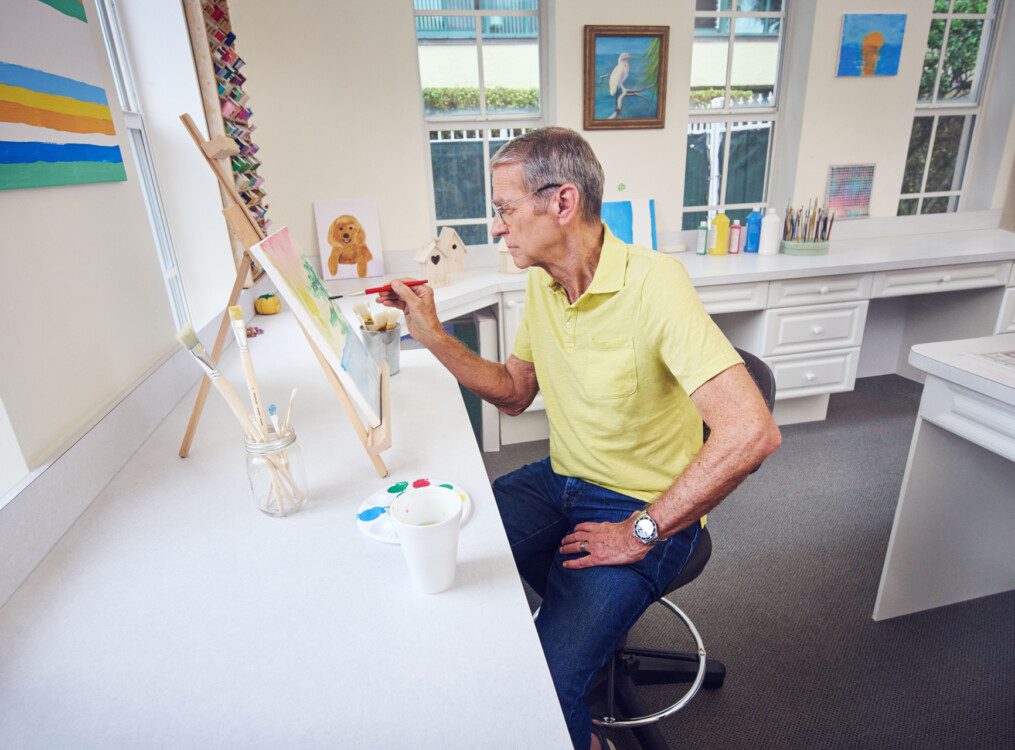 A senior man sitting down and painting