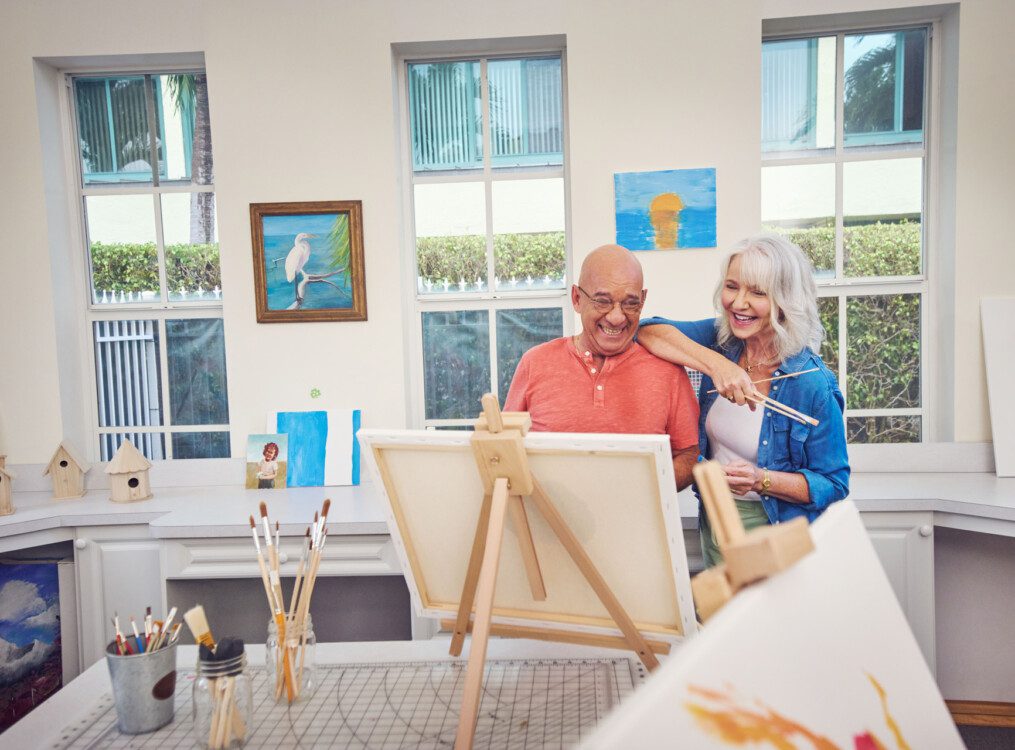 Two seniors laughing and looking at a painting