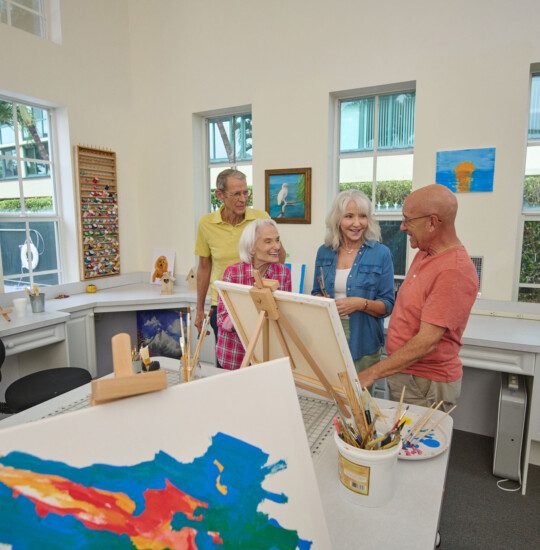 Group of seniors smiling and looking at a painted canvas