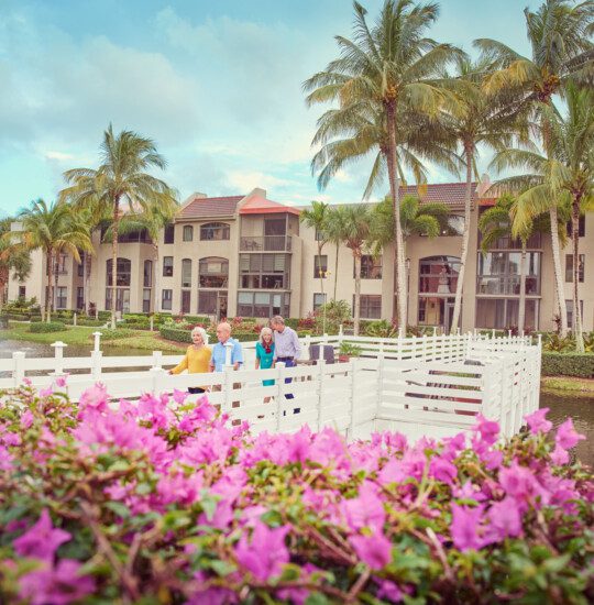 A group of seniors walking down the bridge with flowers in the foreground