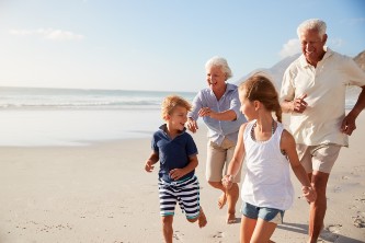 A senior couple and their grandkids running on a beach while laughing