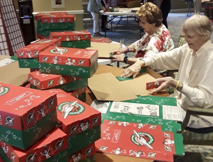 Two senior women folding boxes for charity