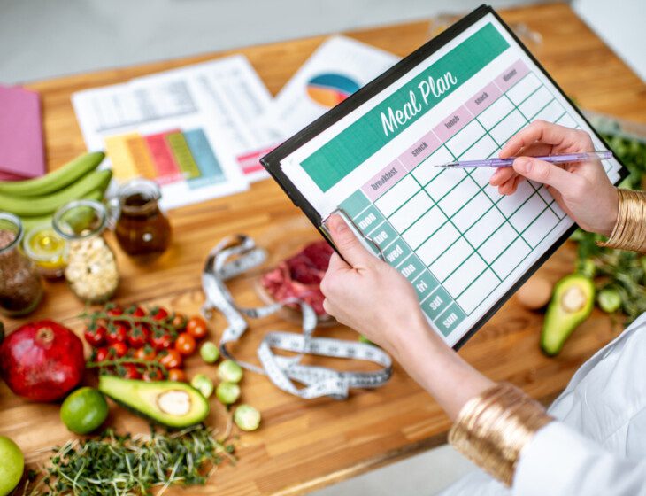 A woman holding a meal plan sheet with healthy food on the table