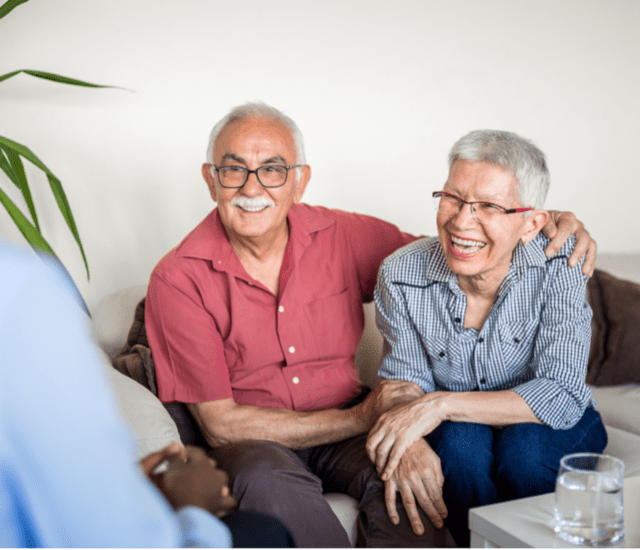 A senior couple talking to someone while on a couch