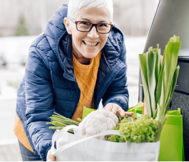 A senior women putting fresh groceries in the back of the trunk