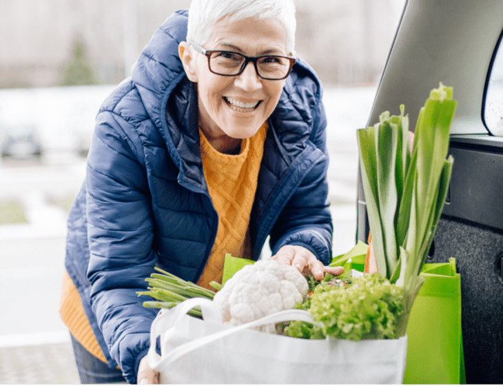 A senior women putting fresh groceries in the back of the trunk