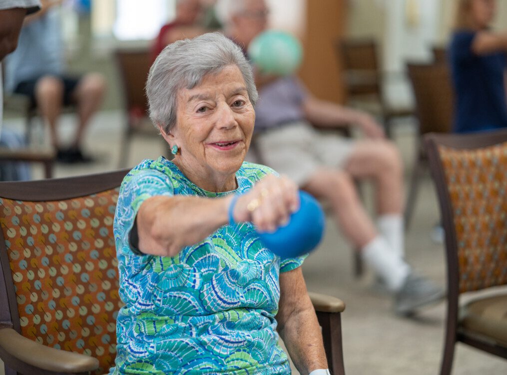 A senior woman sitting down and lifting weights