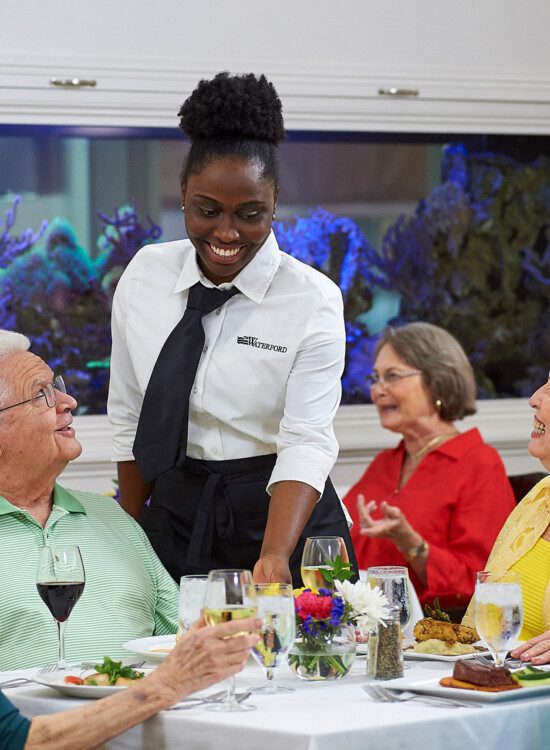 A group of seniors smiling while talking to their server