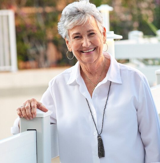 A senior woman smiling and standing on a bridge