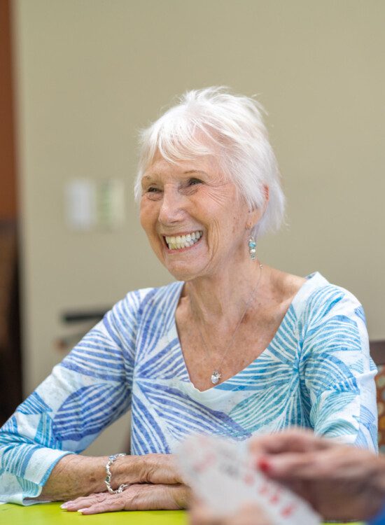 A senior woman smiling while playing cards