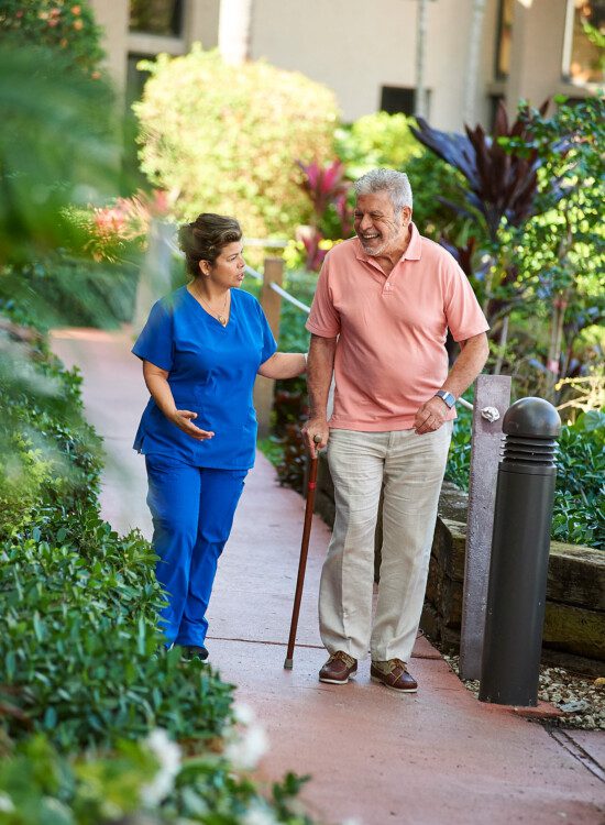 A senior man and skilled nurse walking together and talking