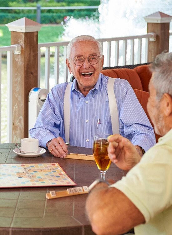 Senior man smiling at friend while playing scrabble