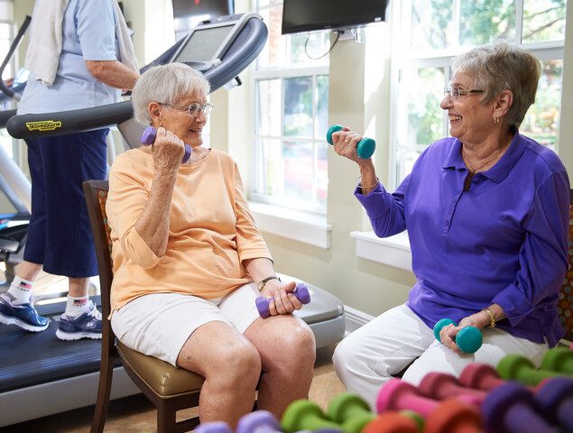 Two senior women in a gym lifting weights