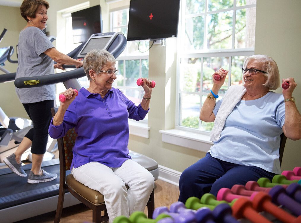 Two senior women in a gym lifting weights