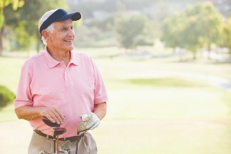 A senior man standing next to a golf bag