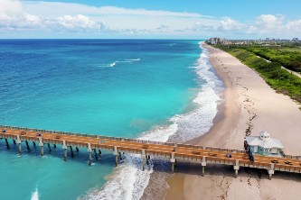 An aerial image of a beach and bridge going to the ocean