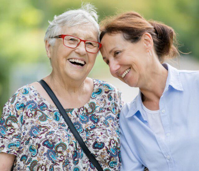 Two senior women smiling while outside