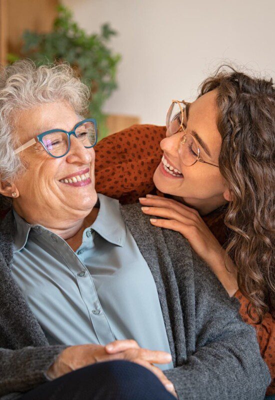 A senior woman laughing with a younger women