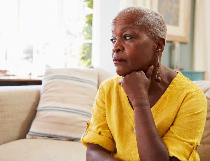 A senior woman sitting on a couch looking into the distance