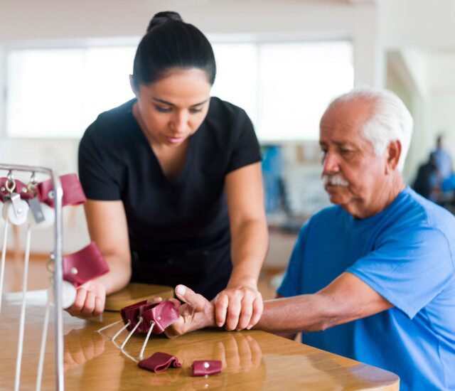 A physical therapist helping a senior man do hand exercises