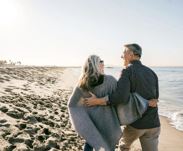 Senior couple walking along the beach near a Florida retirement community