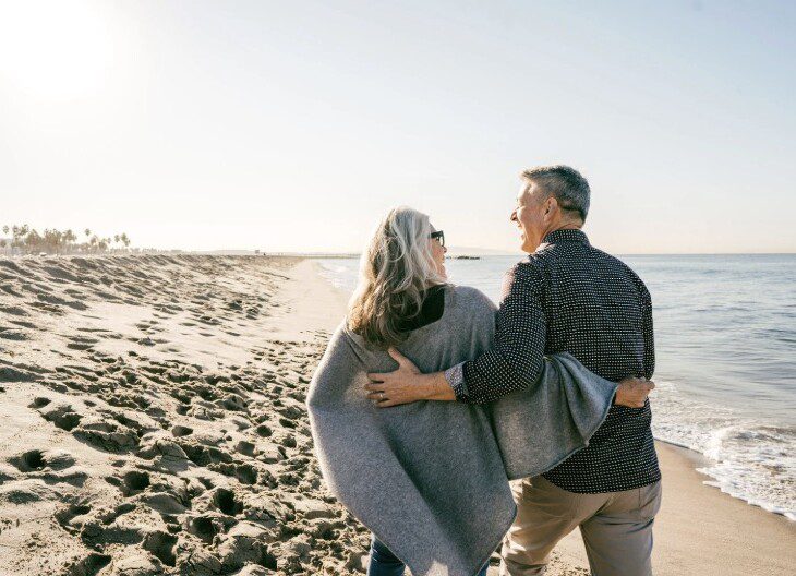 Senior couple walking along the beach near a Florida retirement community